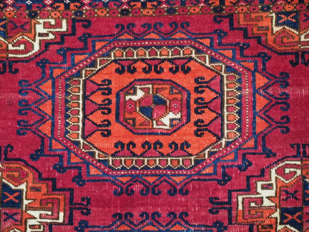 An antique Tekke Turkmen chuval face textile featuring six octagonal turreted guls framed by geometric borders in deep red, navy, and cream wool. View XI