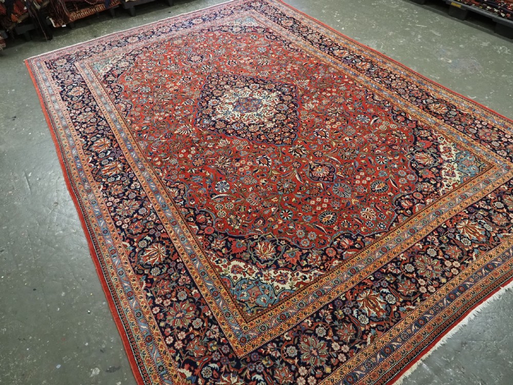 A large hand-knotted antique Kashan carpet featuring a central navy and ivory medallion on a crimson field with intricate floral patterns and layered borders. View II
