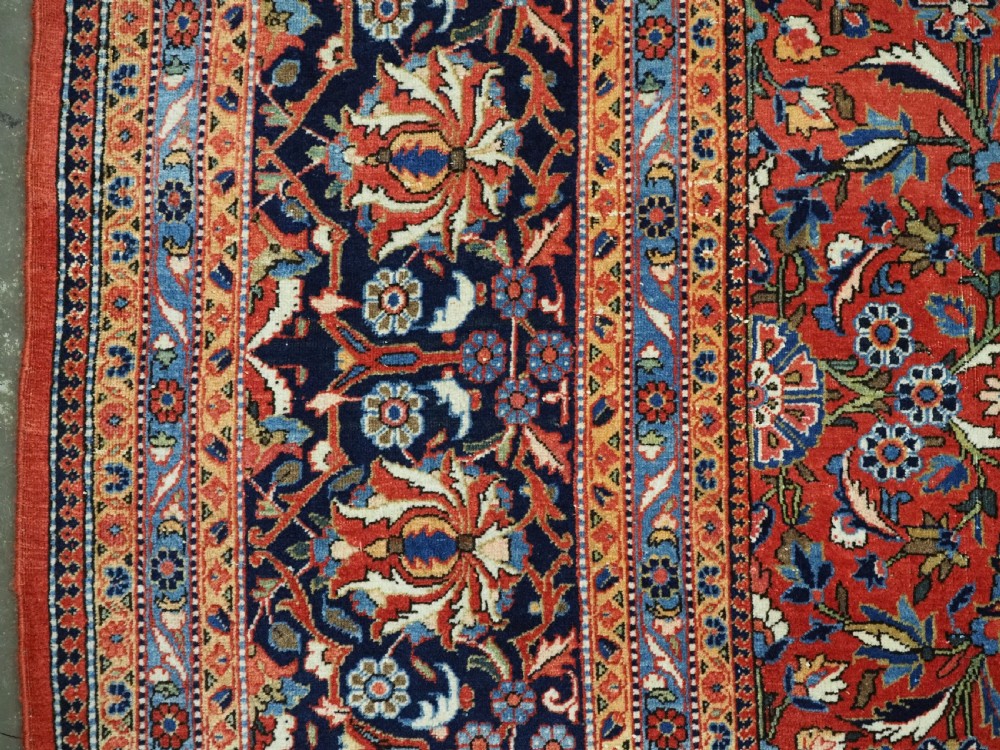 A large hand-knotted antique Kashan carpet featuring a central navy and ivory medallion on a crimson field with intricate floral patterns and layered borders. View VIII