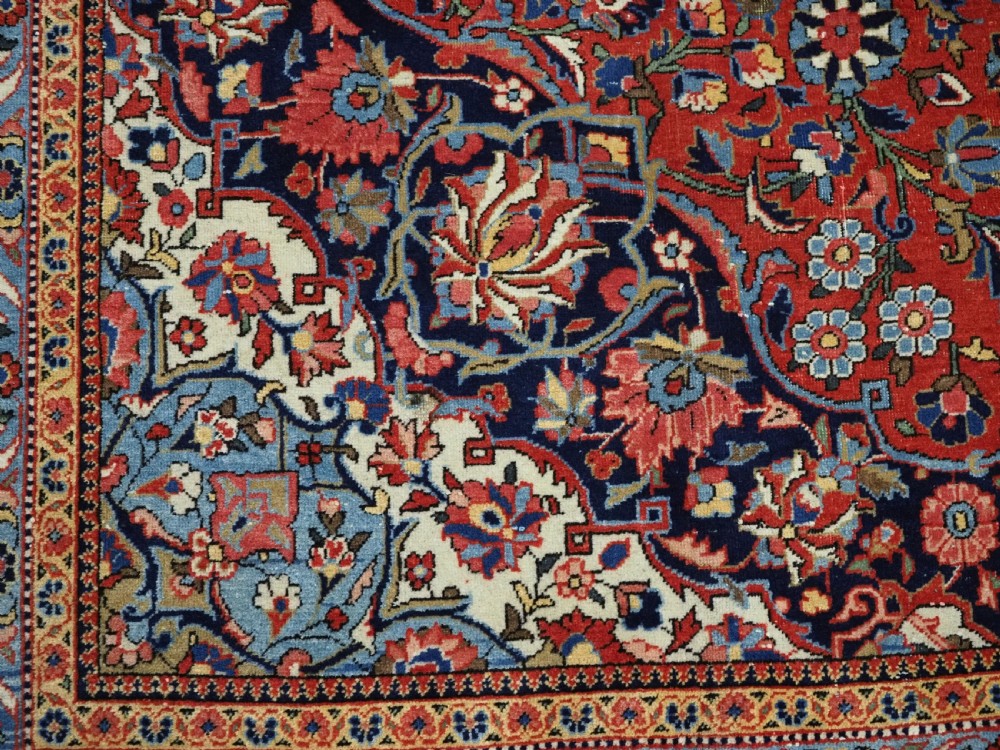 A large hand-knotted antique Kashan carpet featuring a central navy and ivory medallion on a crimson field with intricate floral patterns and layered borders. View XIII
