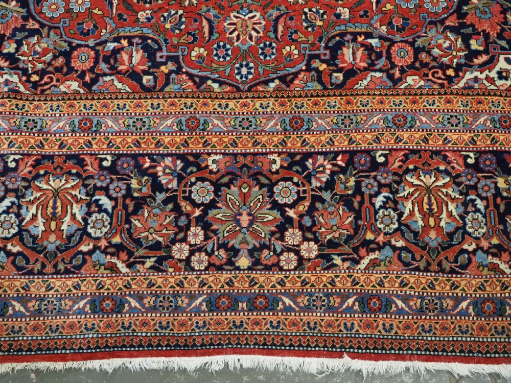 A large hand-knotted antique Kashan carpet featuring a central navy and ivory medallion on a crimson field with intricate floral patterns and layered borders. View XIV