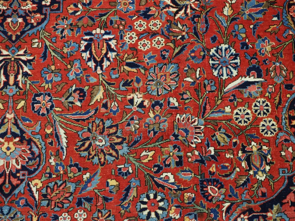A large hand-knotted antique Kashan carpet featuring a central navy and ivory medallion on a crimson field with intricate floral patterns and layered borders. View XV