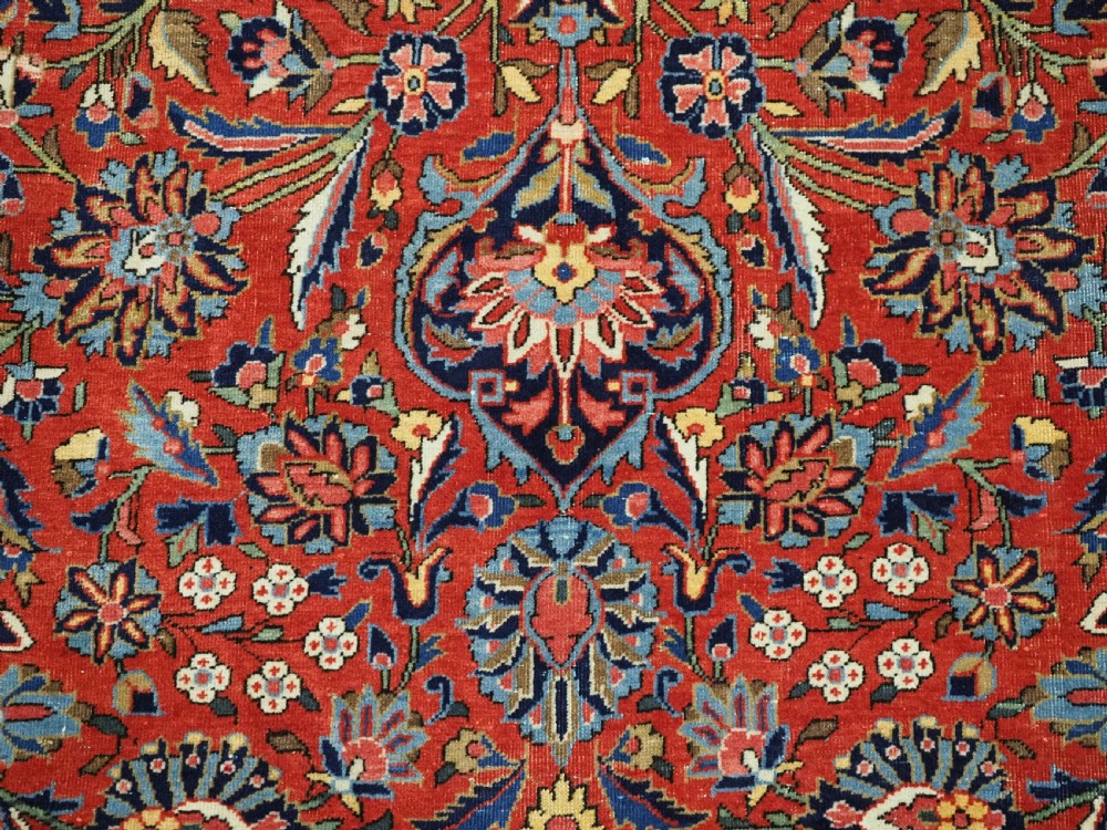 A large hand-knotted antique Kashan carpet featuring a central navy and ivory medallion on a crimson field with intricate floral patterns and layered borders. View XVI