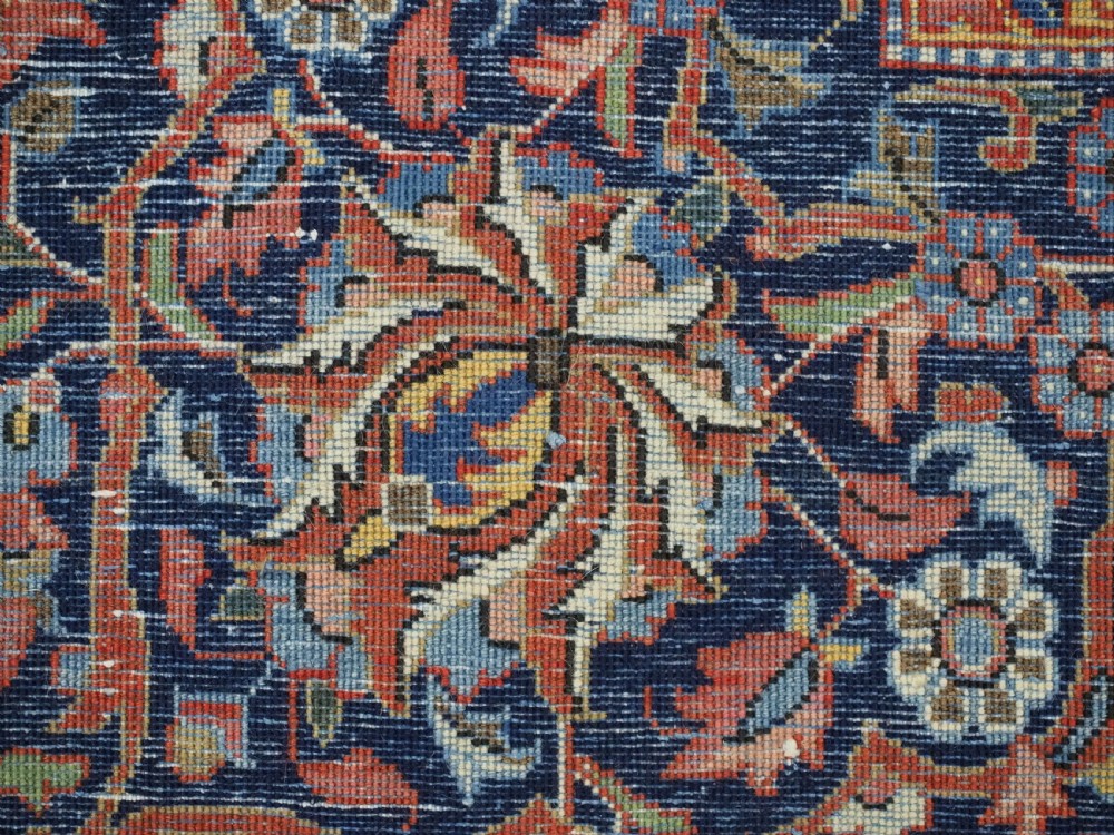 A large hand-knotted antique Kashan carpet featuring a central navy and ivory medallion on a crimson field with intricate floral patterns and layered borders. View XVII