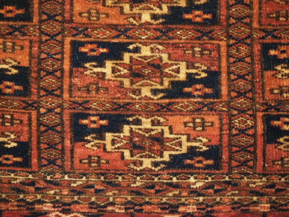 A rectangular Tekke Turkmen woven wool torba bag featuring repeating geometric gul motifs in red, navy, and ivory with a fringed bottom edge. View VI