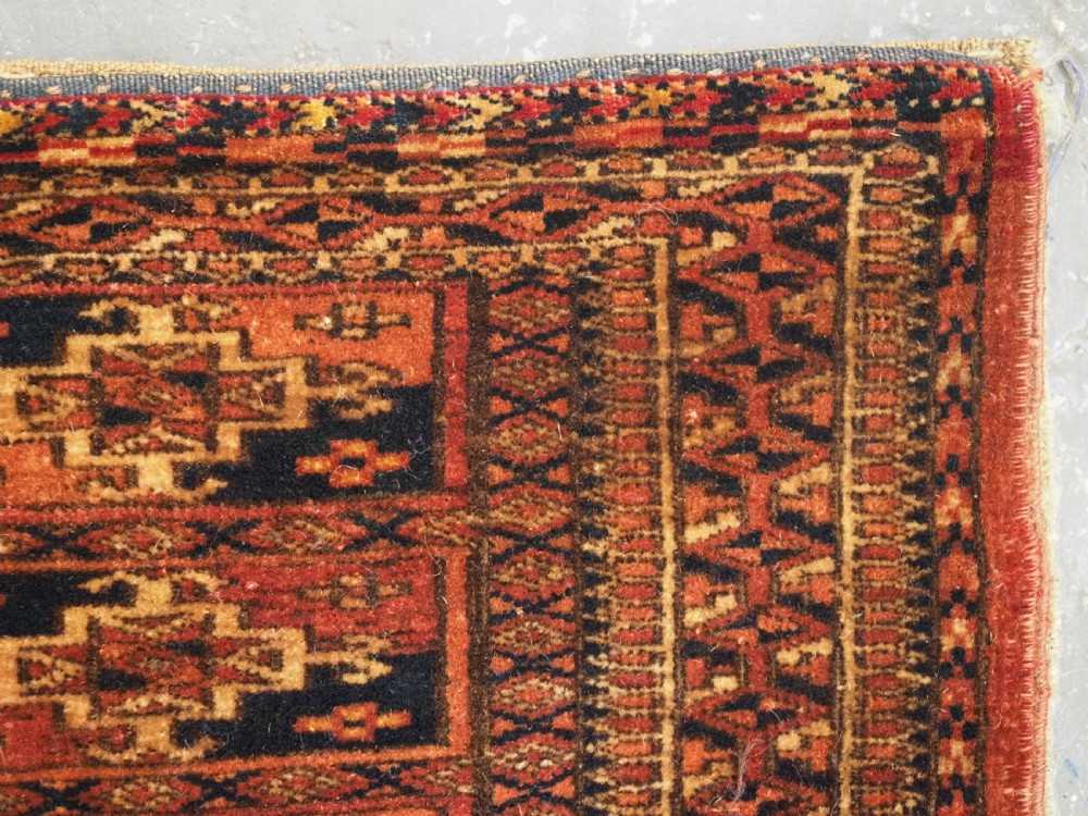 A rectangular Tekke Turkmen woven wool torba bag featuring repeating geometric gul motifs in red, navy, and ivory with a fringed bottom edge. View VII