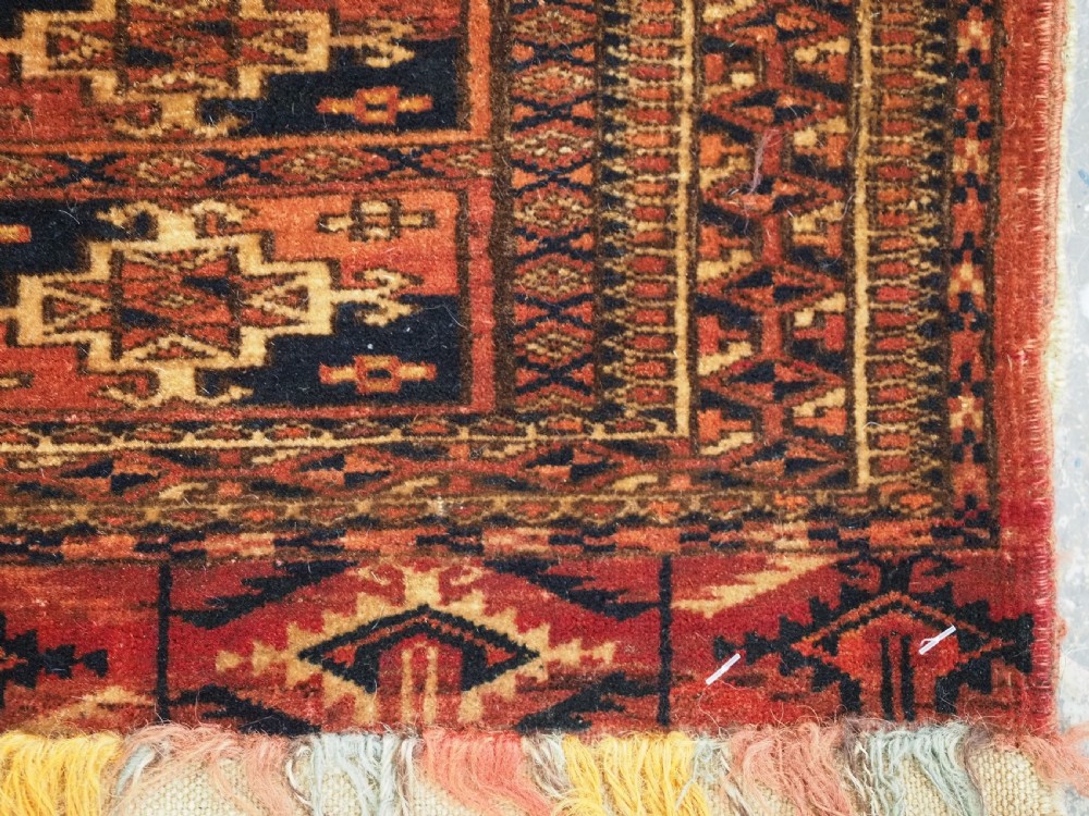 A rectangular Tekke Turkmen woven wool torba bag featuring repeating geometric gul motifs in red, navy, and ivory with a fringed bottom edge. View VIII