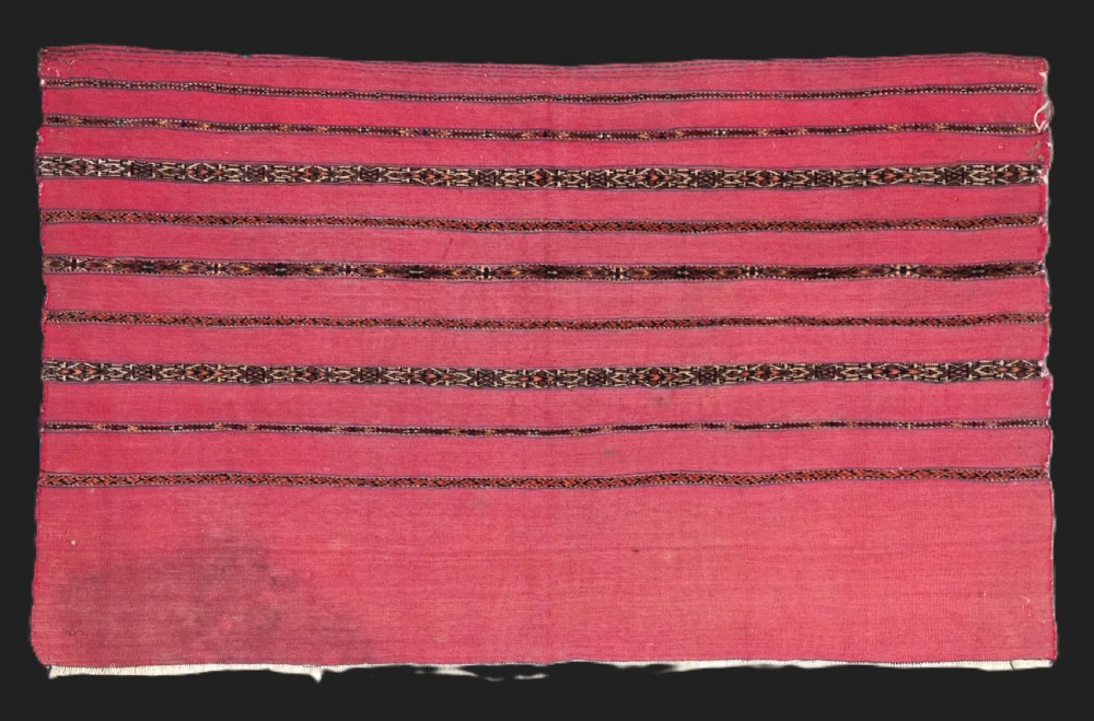 A rectangular red woven Turkmen Tekke chuval face featuring horizontal bands of geometric motifs.