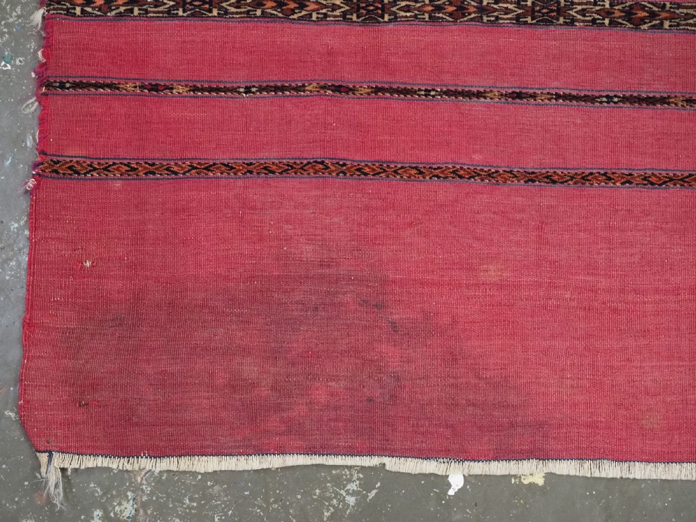 A rectangular red woven Turkmen Tekke chuval face featuring horizontal bands of geometric motifs. View IV