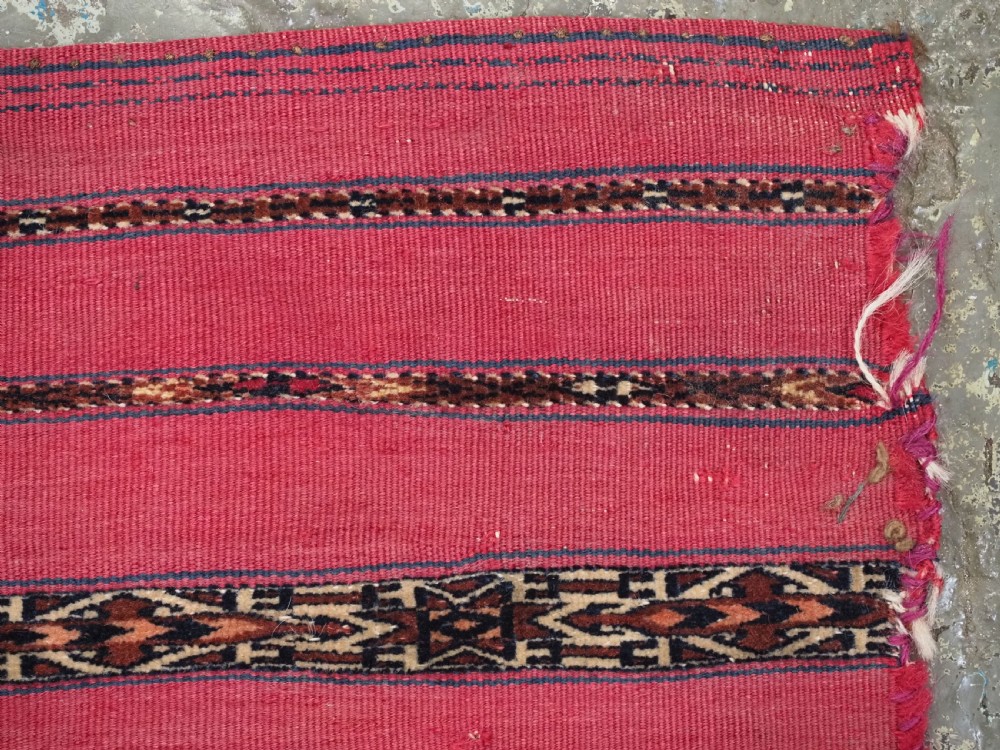 A rectangular red woven Turkmen Tekke chuval face featuring horizontal bands of geometric motifs. View VII