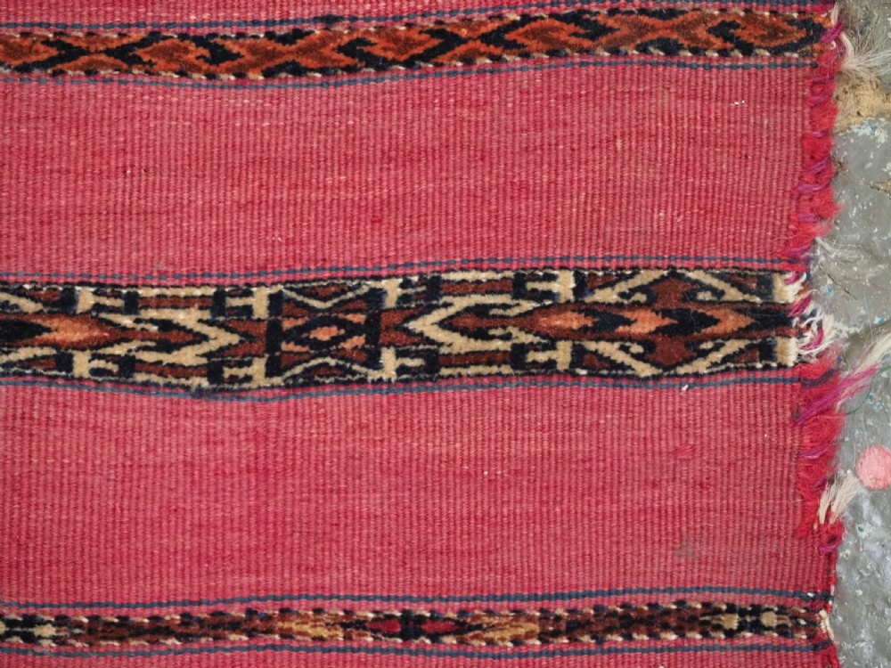 A rectangular red woven Turkmen Tekke chuval face featuring horizontal bands of geometric motifs. View VIII