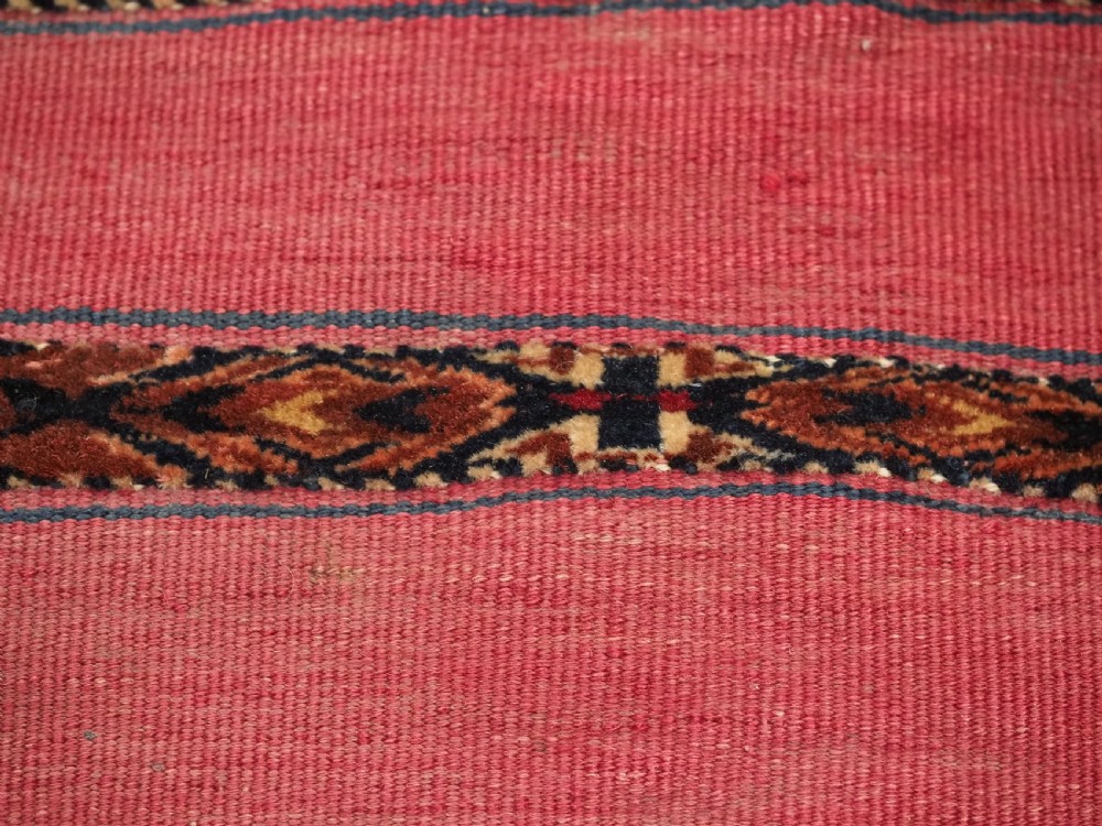 A rectangular red woven Turkmen Tekke chuval face featuring horizontal bands of geometric motifs. View X