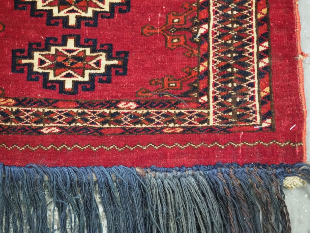 A horizontal crimson red Saryk Turkmen torba textile featuring octagonal Salor guls, intricate geometric borders, and a long dark lower fringe. View VIII