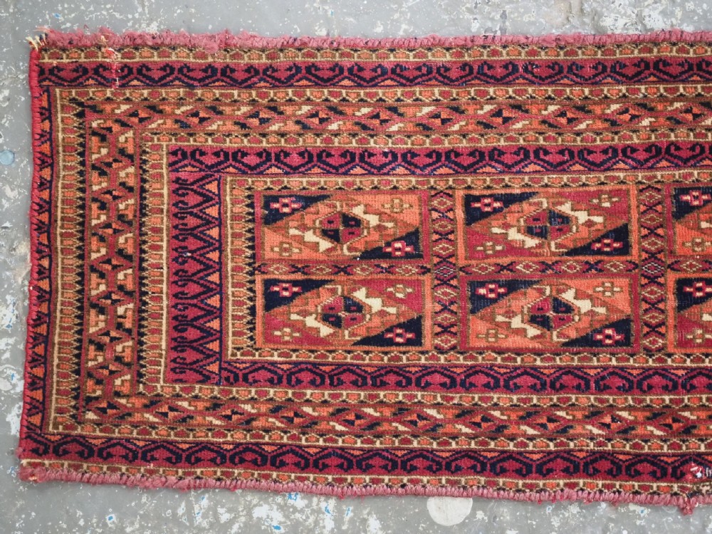 A rectangular hand-knotted wool textile panel featuring geometric Aina Gul motifs in shades of deep crimson, navy blue, and terracotta. View II