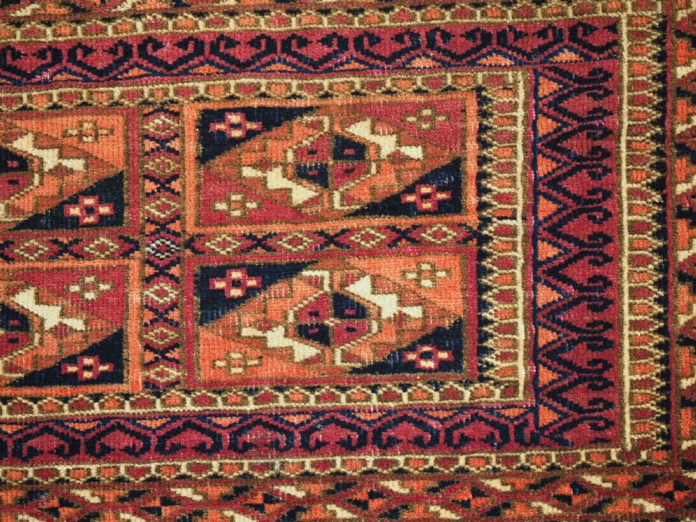A rectangular hand-knotted wool textile panel featuring geometric Aina Gul motifs in shades of deep crimson, navy blue, and terracotta. View VIII