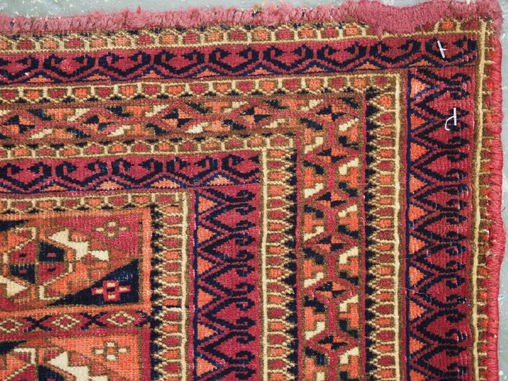 A rectangular hand-knotted wool textile panel featuring geometric Aina Gul motifs in shades of deep crimson, navy blue, and terracotta. View IX