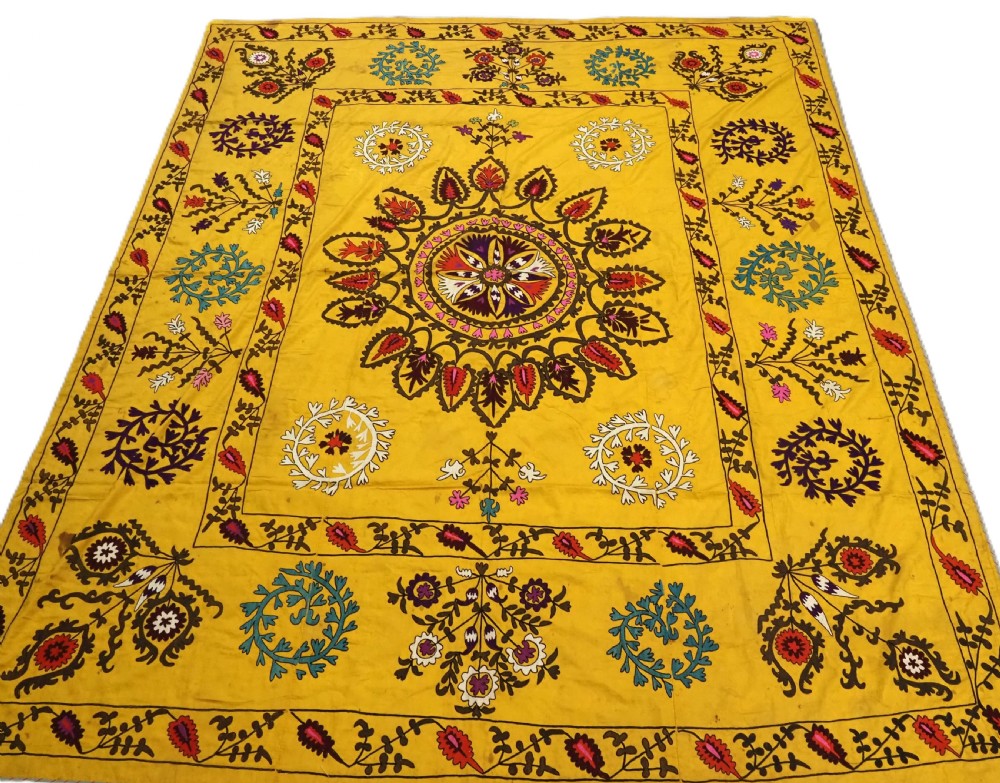 ANTIQUE UZBEK SUZANI, SILK EMBROIDERY ON A YELLOW COTTON GROUND, CIRCA 1900.