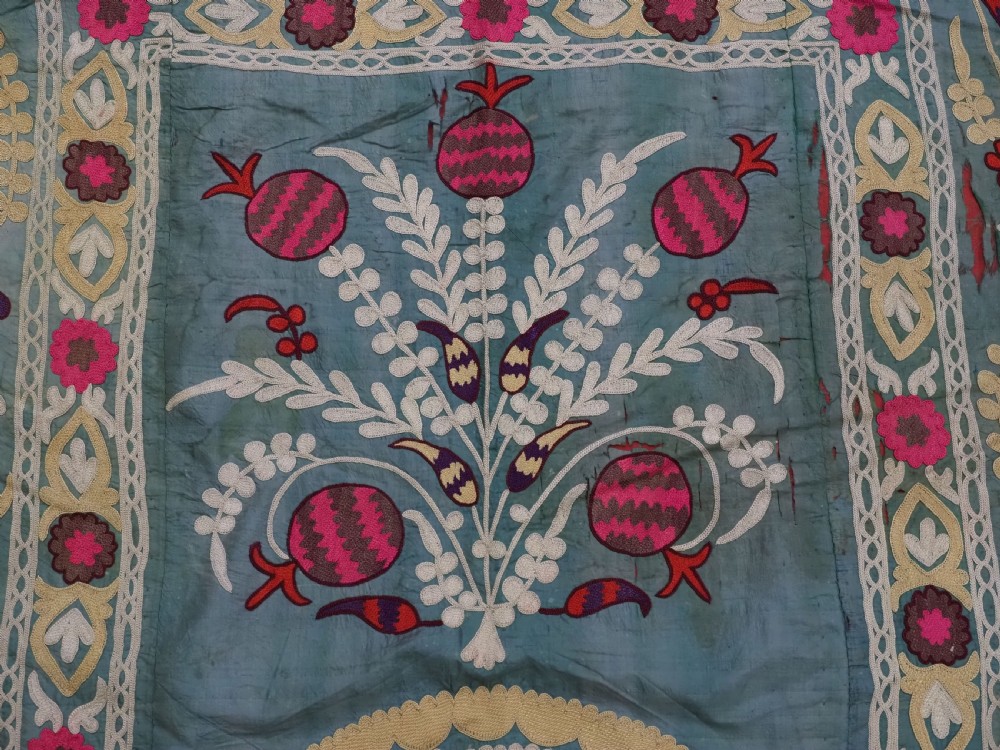 An antique teal silk suzani textile embroidered with pink and red pomegranate motifs, floral medallions, and decorative borders with top fringe. View VII