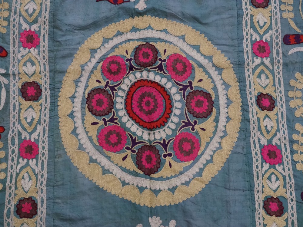 An antique teal silk suzani textile embroidered with pink and red pomegranate motifs, floral medallions, and decorative borders with top fringe. View VIII