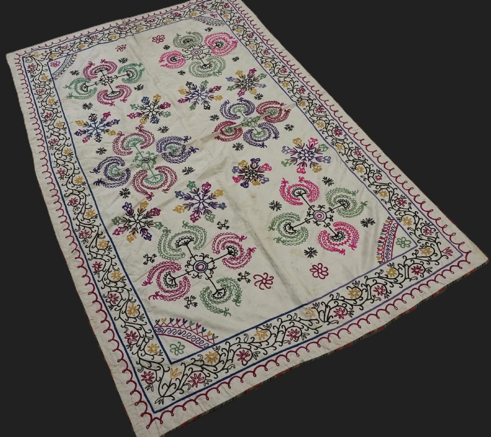 A rectangular antique cream silk Suzani textile featuring hand embroidery with multi-coloured floral roundels and vine borders. View II