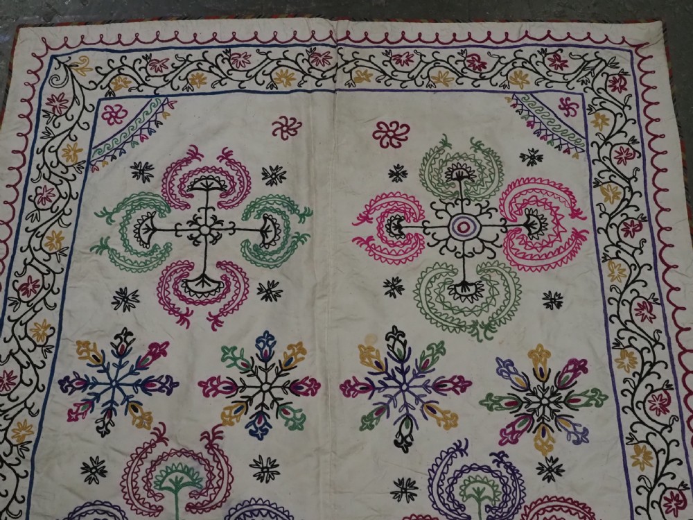 A rectangular antique cream silk Suzani textile featuring hand embroidery with multi-coloured floral roundels and vine borders. View III