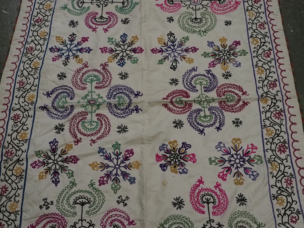 A rectangular antique cream silk Suzani textile featuring hand embroidery with multi-coloured floral roundels and vine borders. View IV