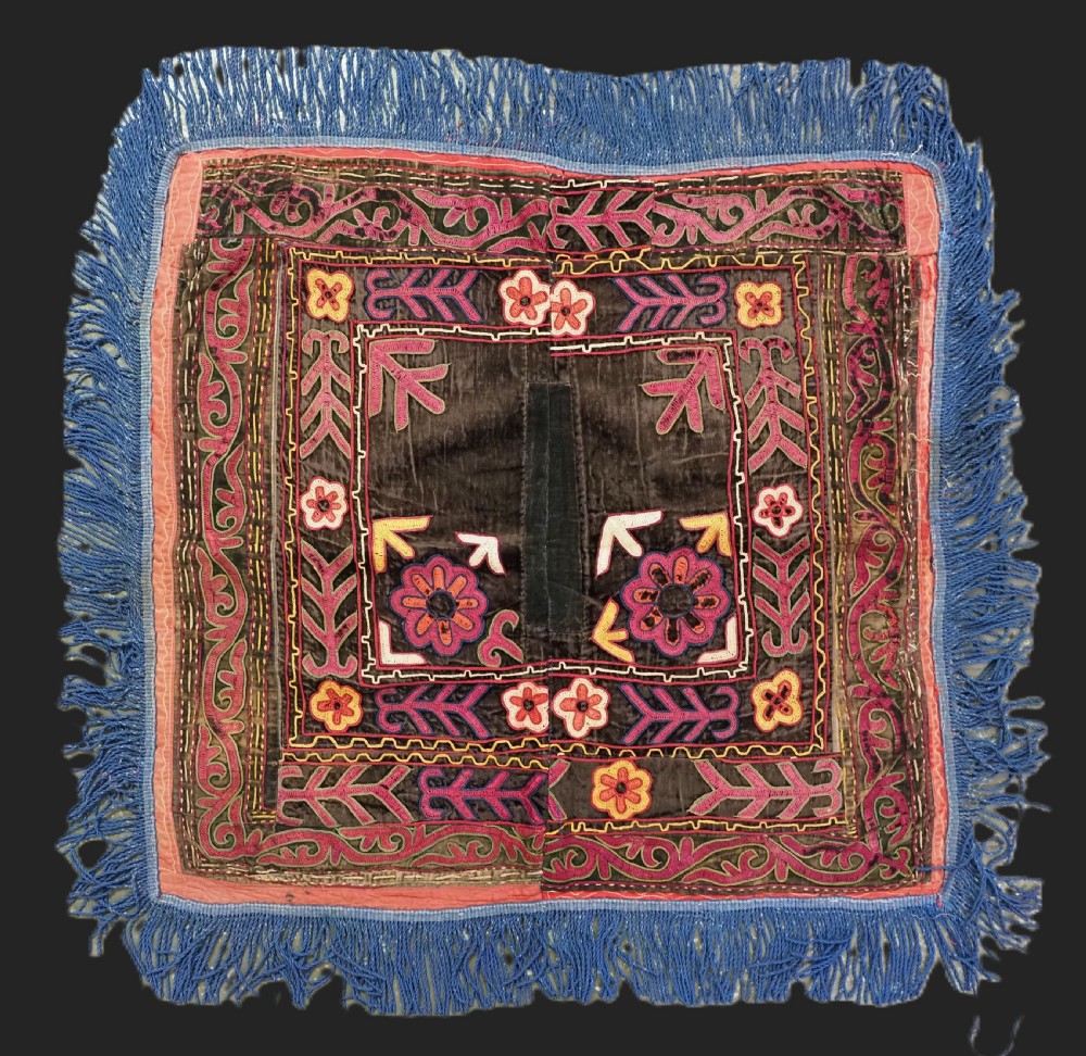 A square antique Uzbek Lakai embroidered panel featuring colourful silk floral motifs on a dark velvet ground, trimmed with a blue fringed border.