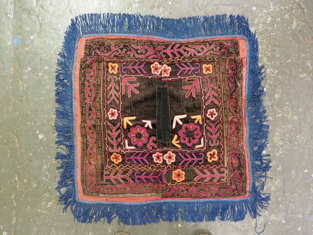 A square antique Uzbek Lakai embroidered panel featuring colourful silk floral motifs on a dark velvet ground, trimmed with a blue fringed border. View II