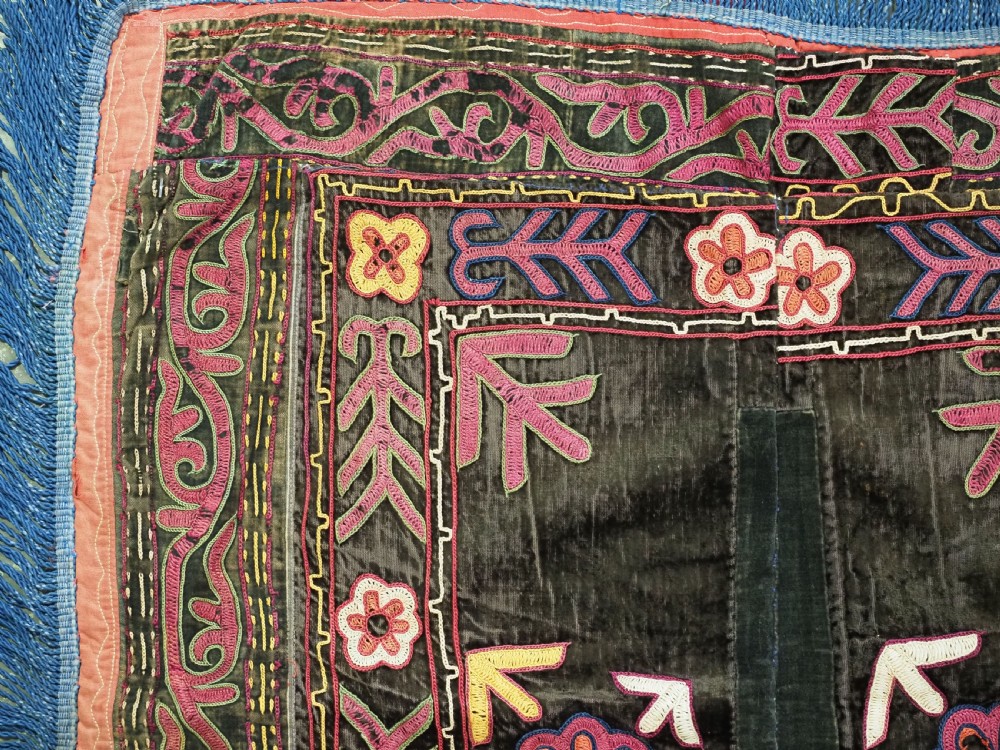 A square antique Uzbek Lakai embroidered panel featuring colourful silk floral motifs on a dark velvet ground, trimmed with a blue fringed border. View III