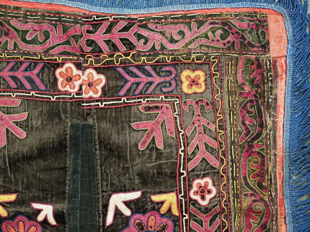 A square antique Uzbek Lakai embroidered panel featuring colourful silk floral motifs on a dark velvet ground, trimmed with a blue fringed border. View IV