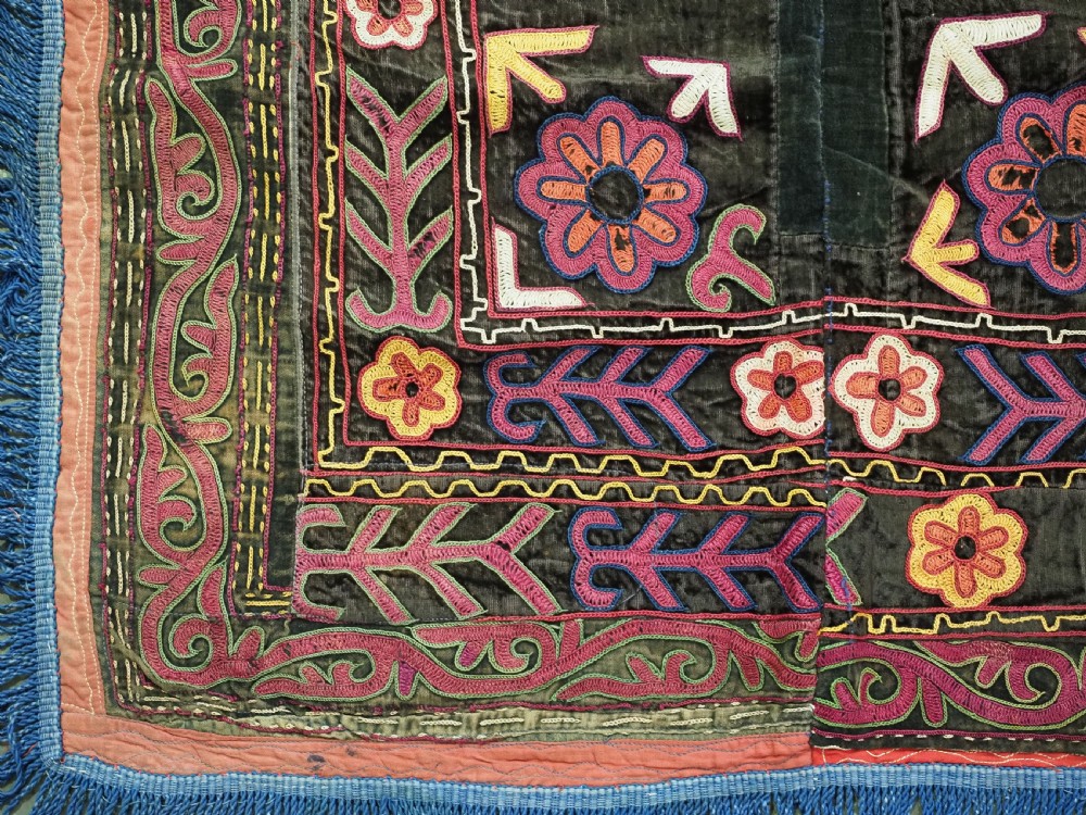 A square antique Uzbek Lakai embroidered panel featuring colourful silk floral motifs on a dark velvet ground, trimmed with a blue fringed border. View V