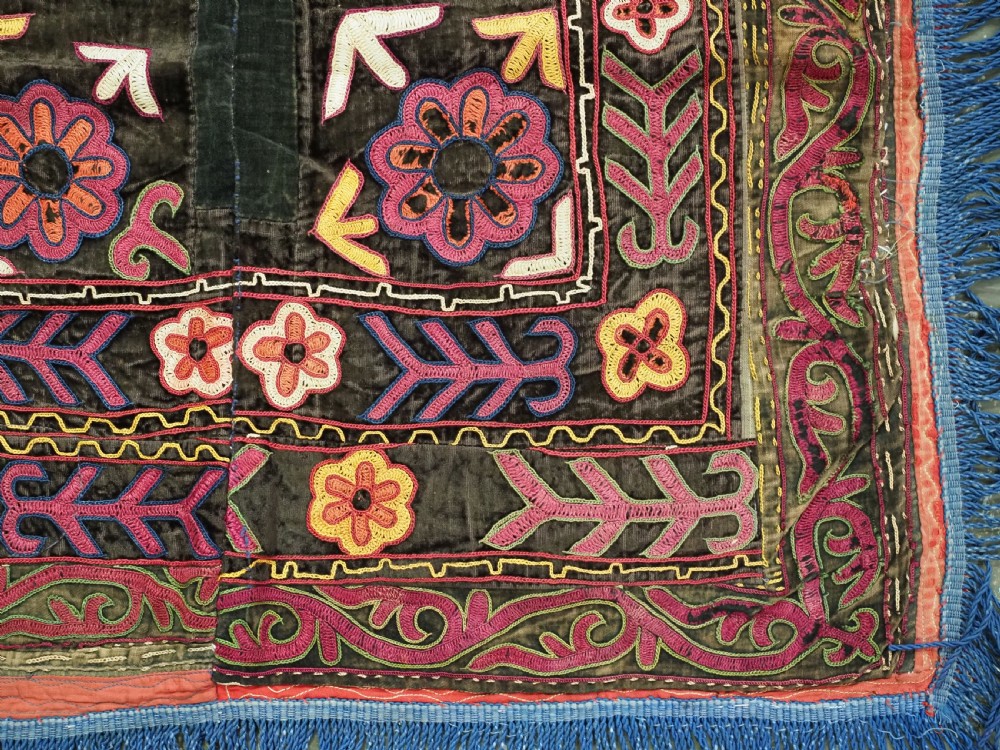 A square antique Uzbek Lakai embroidered panel featuring colourful silk floral motifs on a dark velvet ground, trimmed with a blue fringed border. View VI