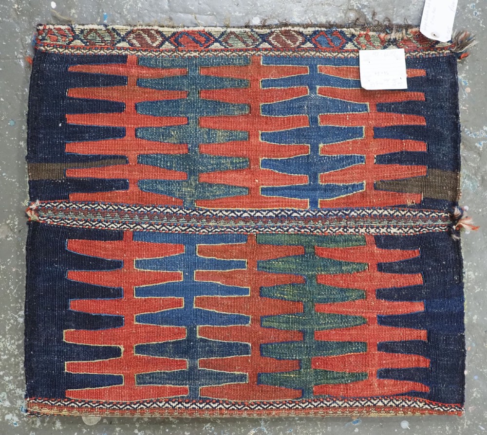 A hand-woven antique Kurdish Jaf bag featuring geometric diamond latch-hook motifs in red, blue, and cream wool with woven loops along the top edge. View II