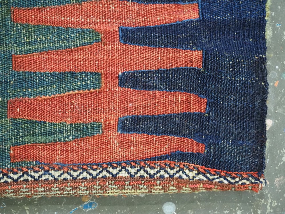 A hand-woven antique Kurdish Jaf bag featuring geometric diamond latch-hook motifs in red, blue, and cream wool with woven loops along the top edge. View XIII