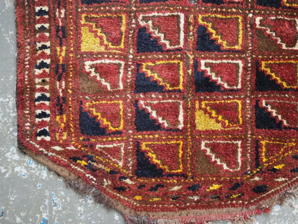 An antique Ersari Turkmen wool saddle cover featuring a grid layout of stepped geometric motifs in red, navy, yellow, and ivory. View III