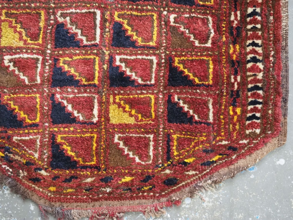 An antique Ersari Turkmen wool saddle cover featuring a grid layout of stepped geometric motifs in red, navy, yellow, and ivory. View V
