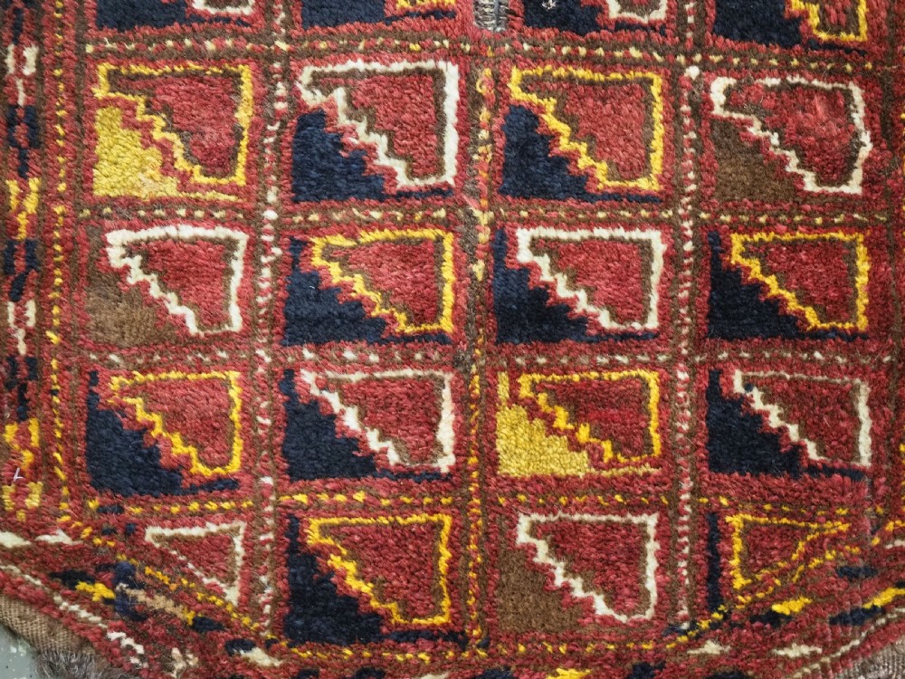 An antique Ersari Turkmen wool saddle cover featuring a grid layout of stepped geometric motifs in red, navy, yellow, and ivory. View VII
