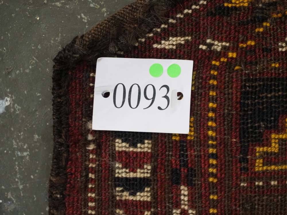 An antique Ersari Turkmen wool saddle cover featuring a grid layout of stepped geometric motifs in red, navy, yellow, and ivory. View X