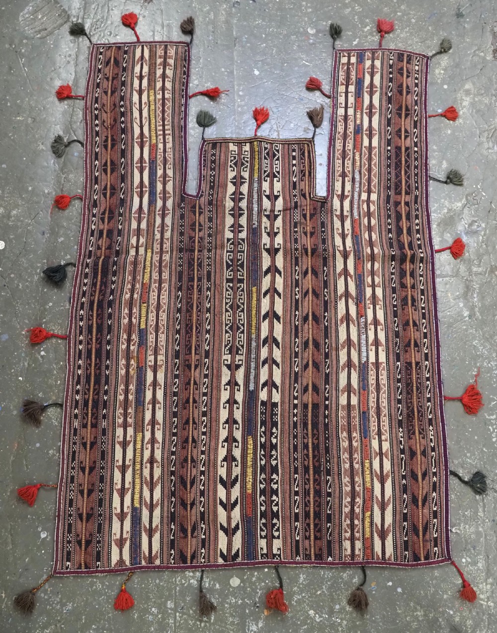 A flat-weave woven wool Northern Afghan ceremonial horse blanket featuring brown, cream, red, and blue geometric stripes with wool tassels along the edges.