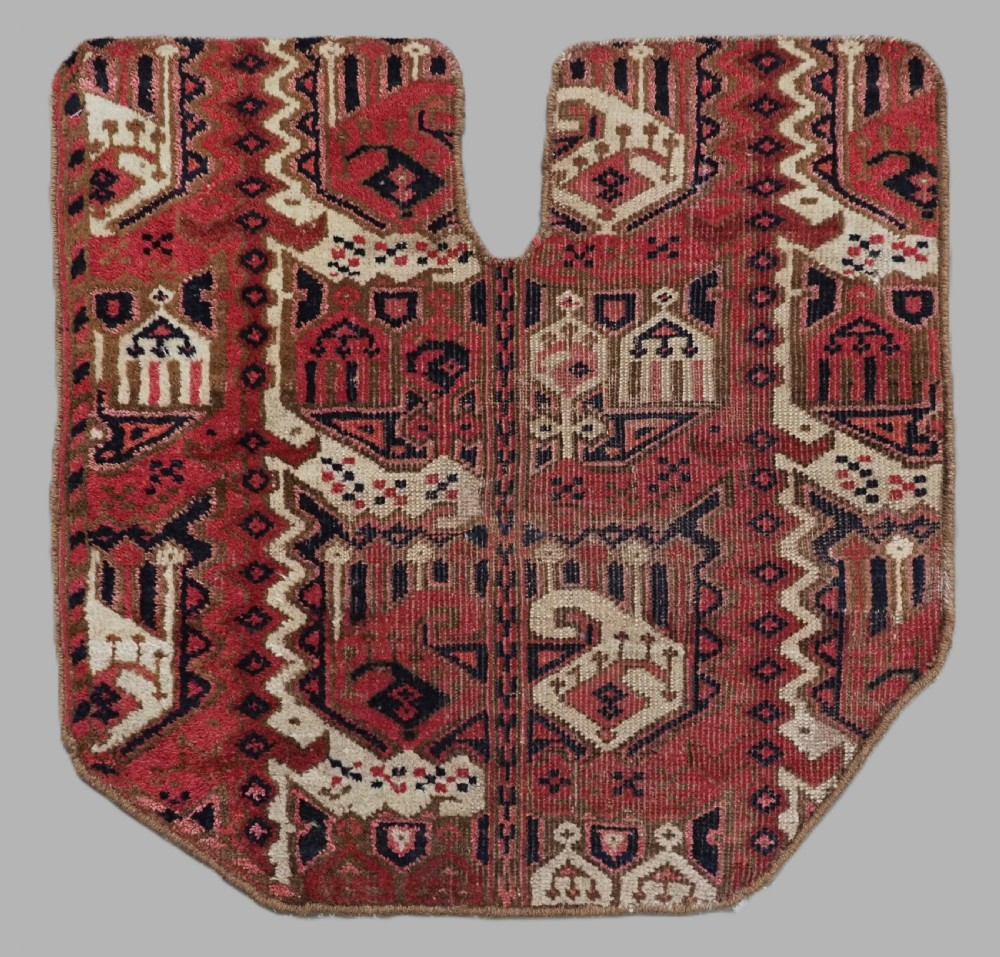A late nineteenth-century Ersari Beshir Turkmen saddle rug featuring red, cream, and dark navy geometric patterns with a central top notch.