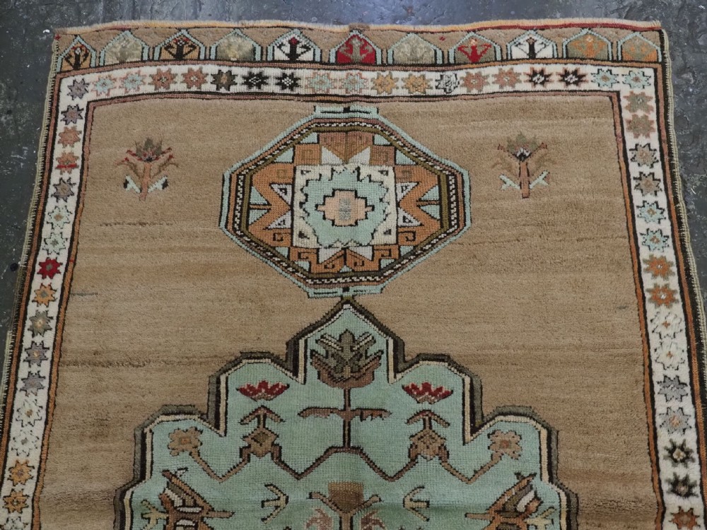 An antique hand-knotted Turkish Konya Karapinar rug featuring a camel wool field and geometric medallions in turquoise and terracotta. View III