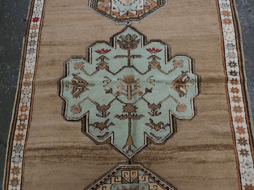 An antique hand-knotted Turkish Konya Karapinar rug featuring a camel wool field and geometric medallions in turquoise and terracotta. View IV