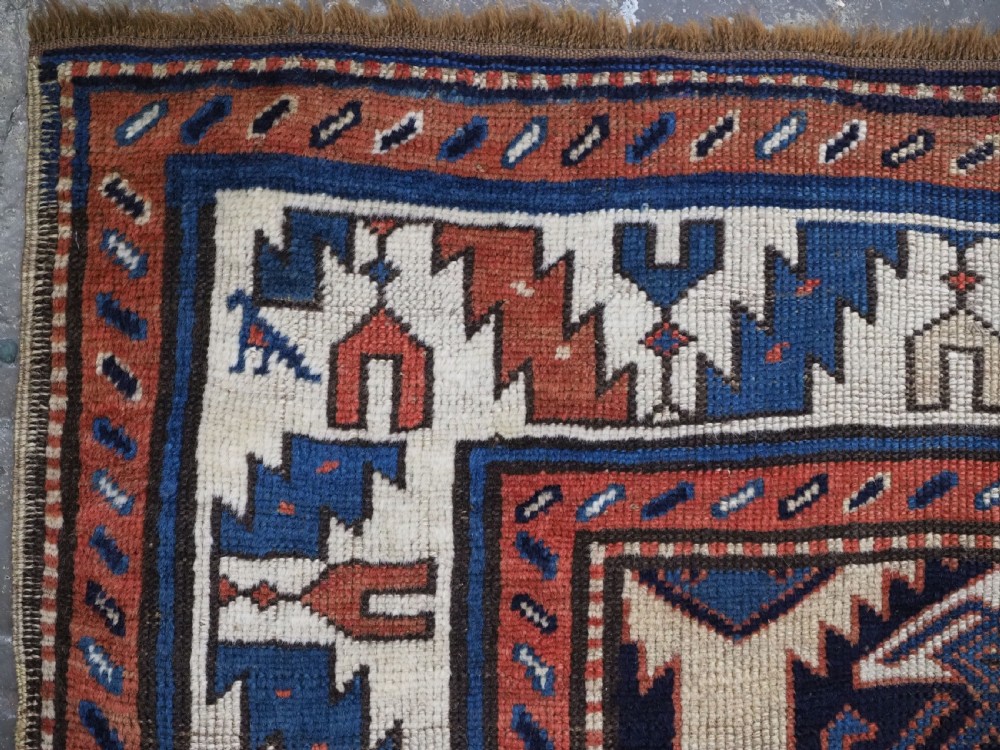 An antique Caucasian wool rug runner featuring a central geometric lattice pattern in navy blue and cream within multiple decorative borders. View VIII