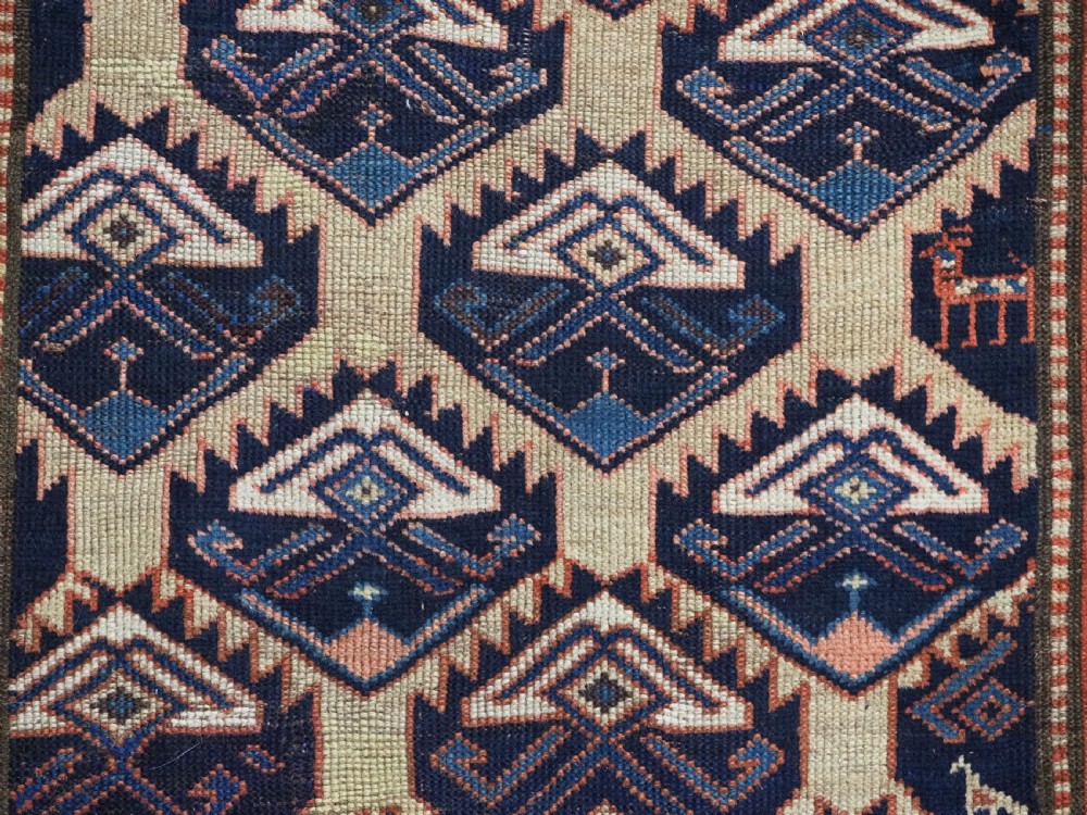An antique Caucasian wool rug runner featuring a central geometric lattice pattern in navy blue and cream within multiple decorative borders. View XI