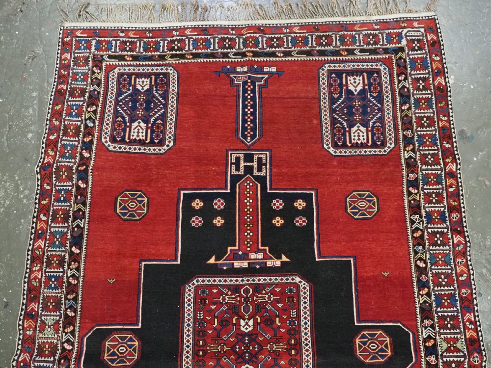 An antique Caucasian Konagkend hand-knotted wool rug featuring a large dark cruciform central medallion on a deep red ground with geometric borders and fringe. View III