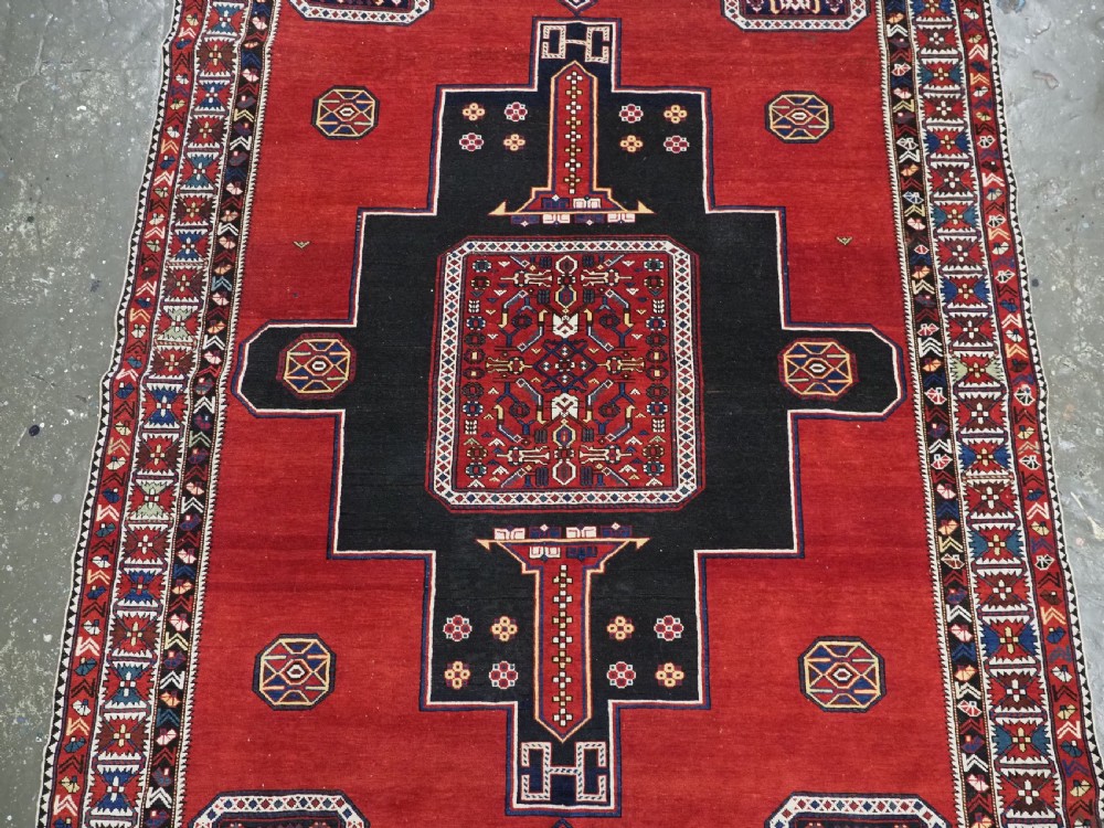 An antique Caucasian Konagkend hand-knotted wool rug featuring a large dark cruciform central medallion on a deep red ground with geometric borders and fringe. View IV