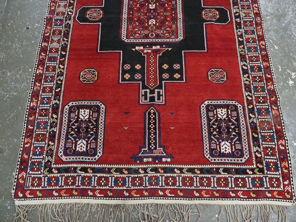An antique Caucasian Konagkend hand-knotted wool rug featuring a large dark cruciform central medallion on a deep red ground with geometric borders and fringe. View V