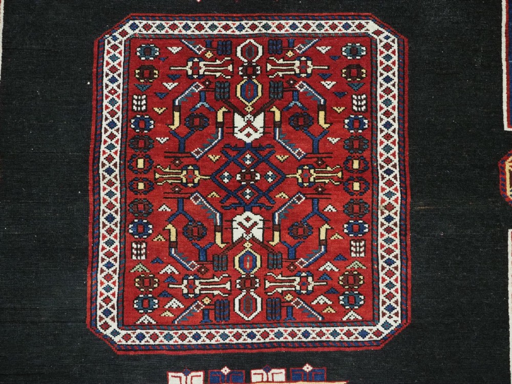 An antique Caucasian Konagkend hand-knotted wool rug featuring a large dark cruciform central medallion on a deep red ground with geometric borders and fringe. View XI