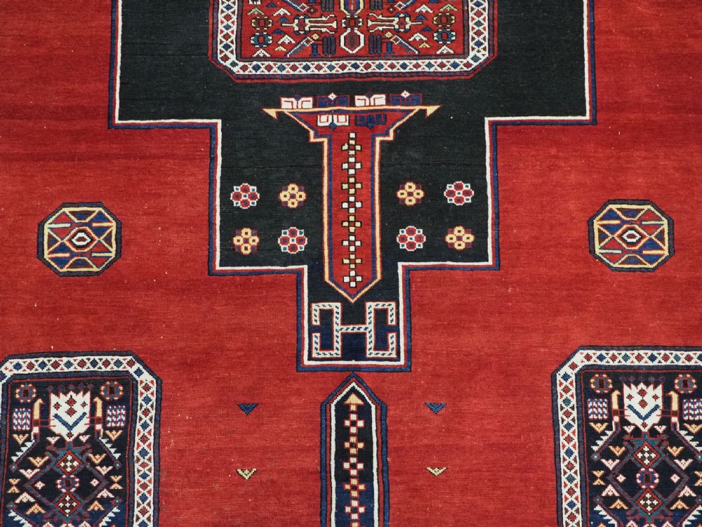An antique Caucasian Konagkend hand-knotted wool rug featuring a large dark cruciform central medallion on a deep red ground with geometric borders and fringe. View XII