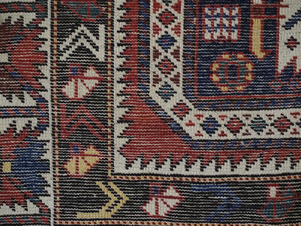 An antique Caucasian Konagkend hand-knotted wool rug featuring a large dark cruciform central medallion on a deep red ground with geometric borders and fringe. View XVI